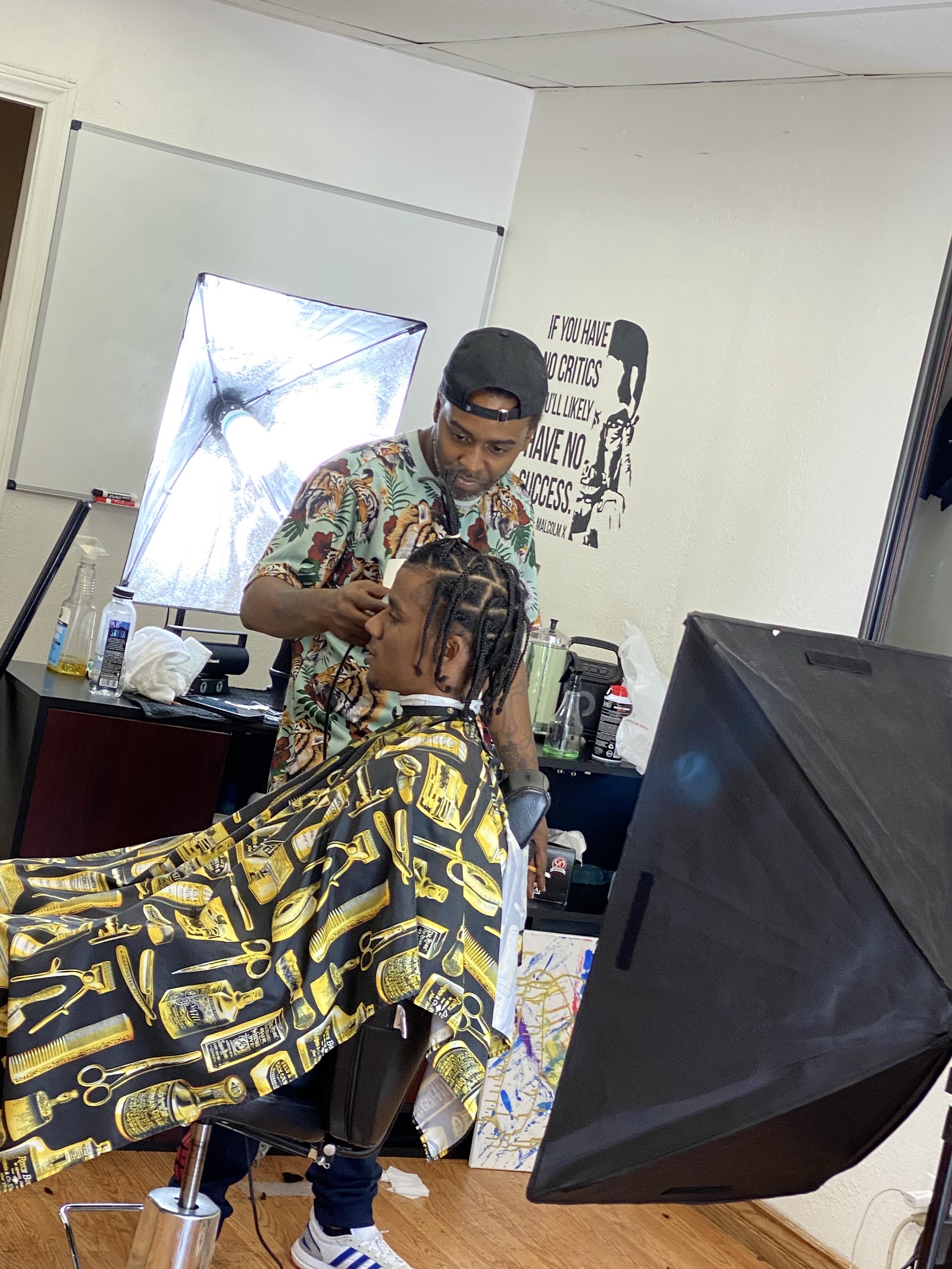 Barber lining up a client with braids in the shop